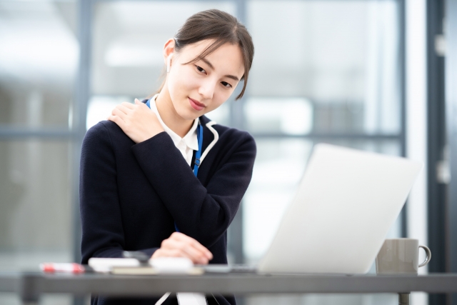 デスクワーク中に肩が凝る女性